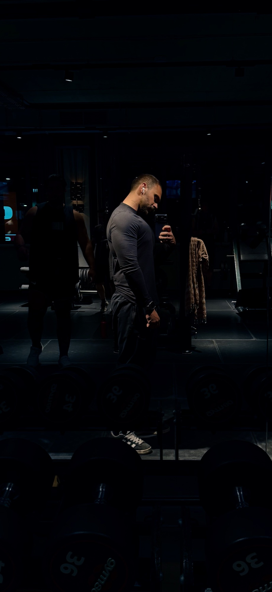Dunkles Spiegelporträt zwischen den Hanteln im Gym